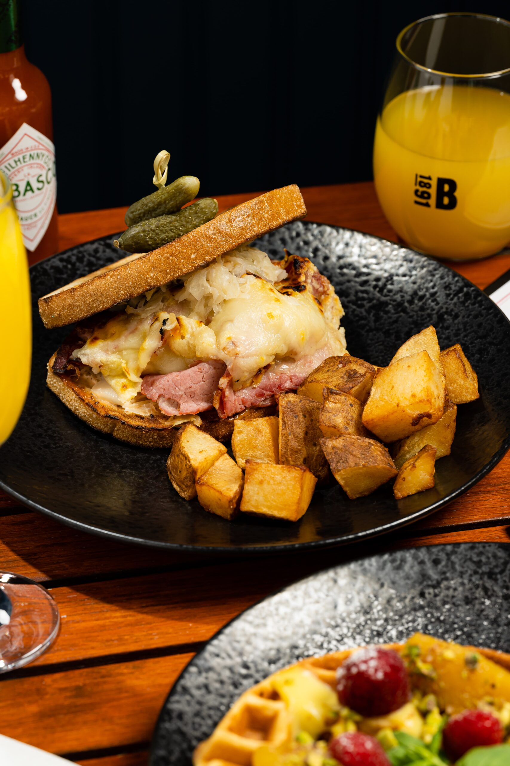 black dining plate with a breakfast sandwich and homefries