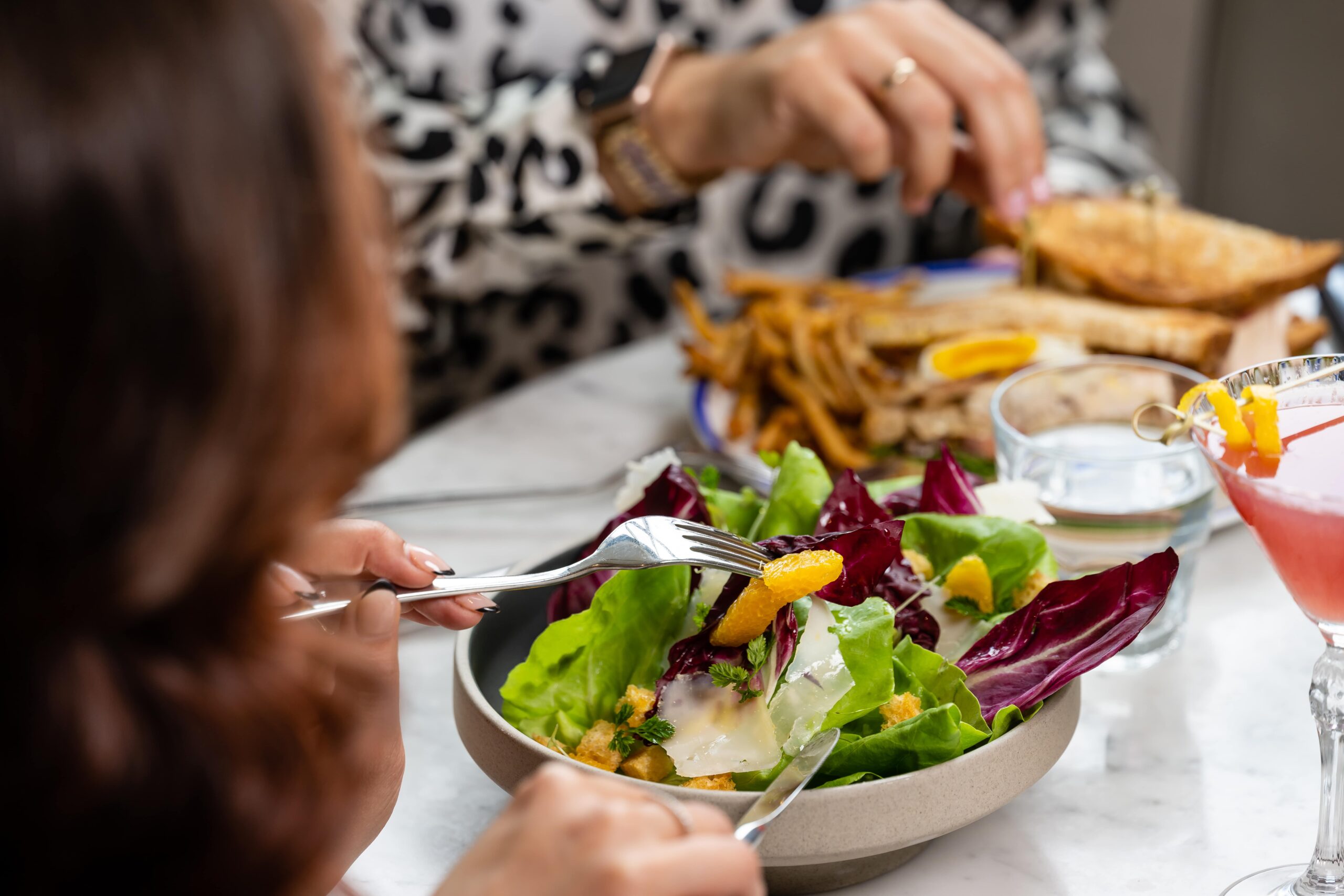 a woman digging into a mixed green salad at a restaurant