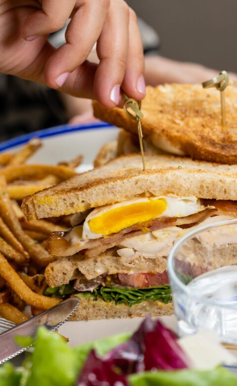 a woman eating a breakfast sandwich in a restaurant with a side of french fries