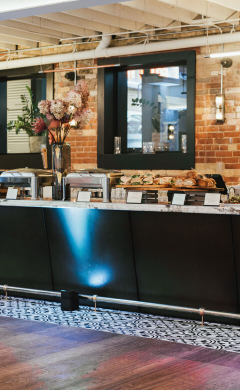 counter with various buffet items on top of it in front of brick wall