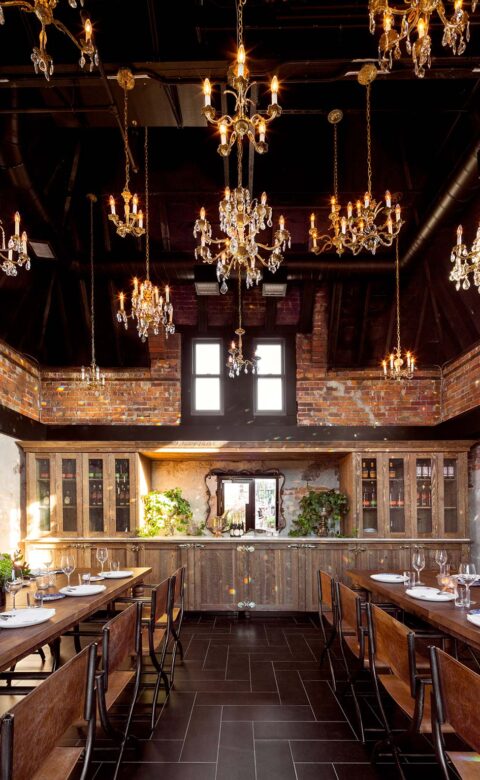 event space with 9 chandeliers hanging overhead and set wooden tables to the left and right