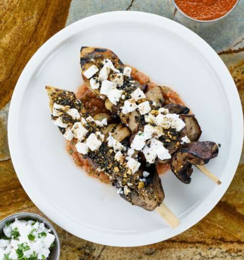 two skewers of meat topped with feta