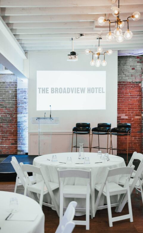 a round table with white chairs in front of a projector screen