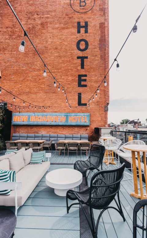 Rooftop patio at The Broadview Hotel with lounge seating, string lights, and a vintage brick hotel sign.