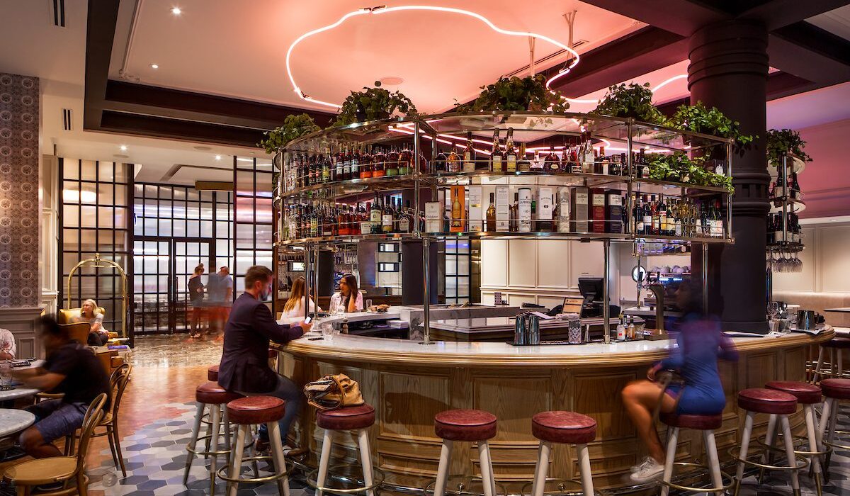 Cozy bar and lounge area with ambient pink lighting and overhead fixtures.