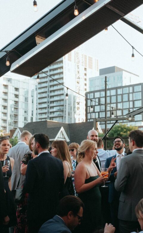 Guests socialising at an evening reception on the open-air rooftop patio.