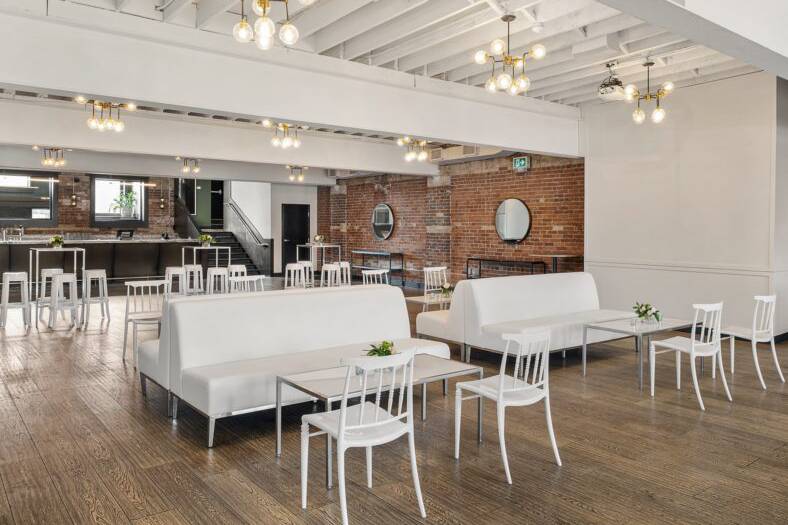 White leather sofa seating area set up in Lincoln Hall with coffee tables and wooden flooring.