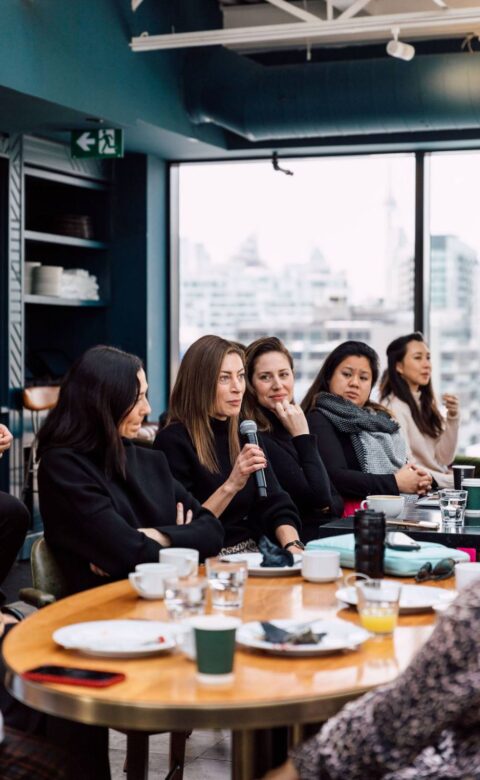 Speakers participating in a panel discussion around a table at a private event.