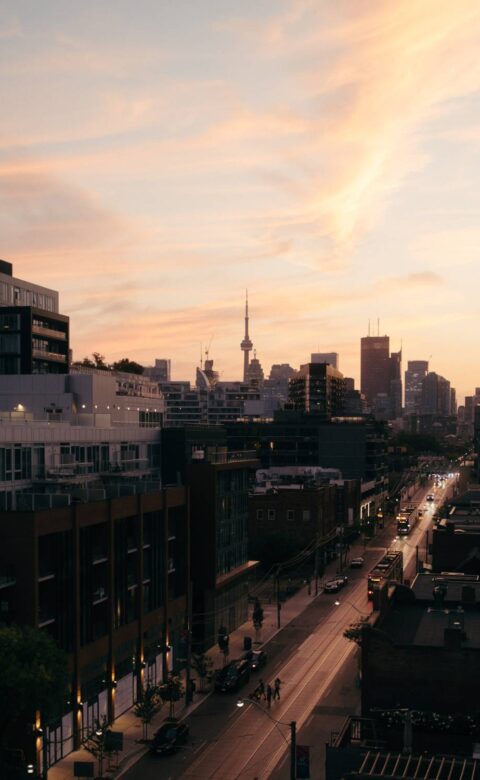 Toronto skyline at sunset with the CN Tower and downtown streets viewed from above.