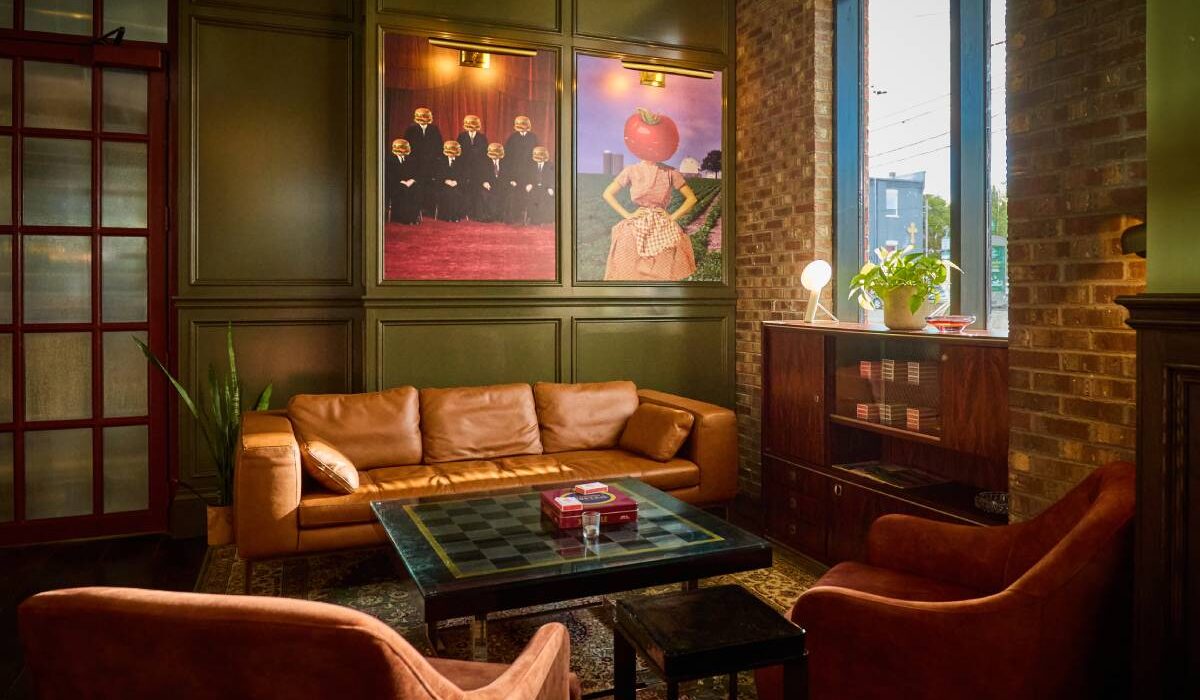 Cozy lounge with leather seating, a chess table, eclectic artwork, and exposed brick walls.